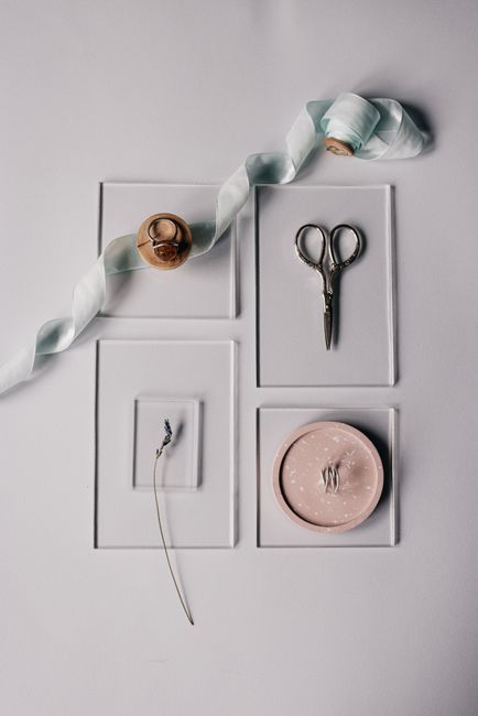 Flat lay of ribbon, lavender, scissors, and ornaments on a minimalist surface.