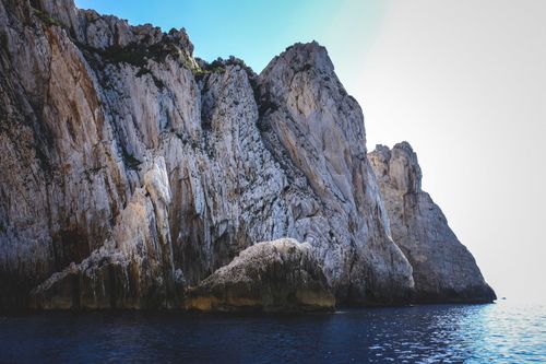 Free Majestic sea cliffs rising from the deep blue ocean on a sunny day, perfect for summer travel. Stock Photo
