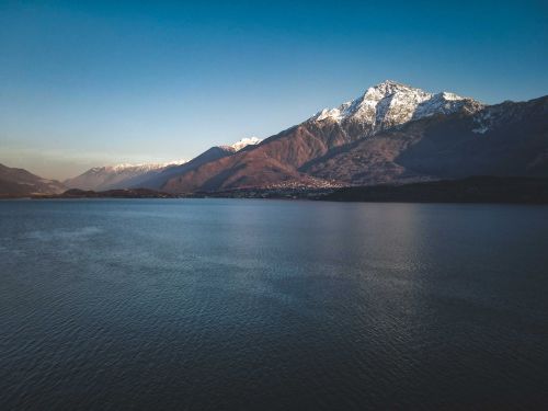 Free Peaceful landscape of a snow-capped mountain and tranquil lake under a blue sky. Stock Photo
