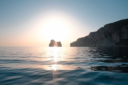 Peaceful sunrise over calm sea with rock formations and cliffs. Perfect for nature enthusiasts.