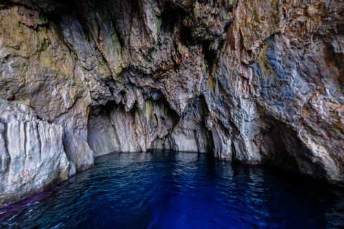 Free Explore the beauty of a natural cave with still blue water and remarkable rock formations. Stock Photo