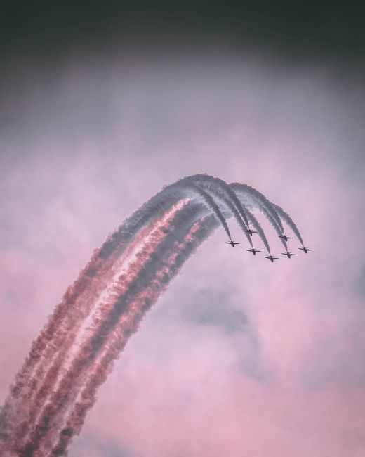 Stunning aerobatic performance with aircraft leaving colorful smoke trails in the sky.