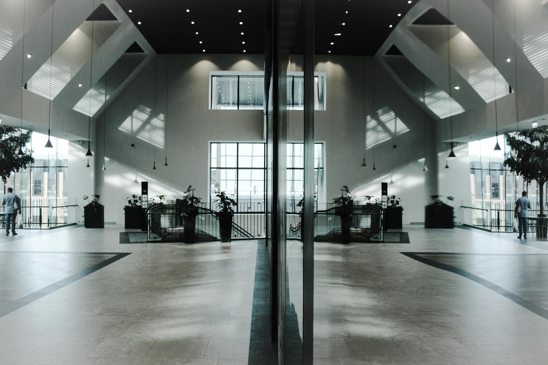 A modern, spacious indoor lobby featuring stunning architectural design and symmetrical reflections.