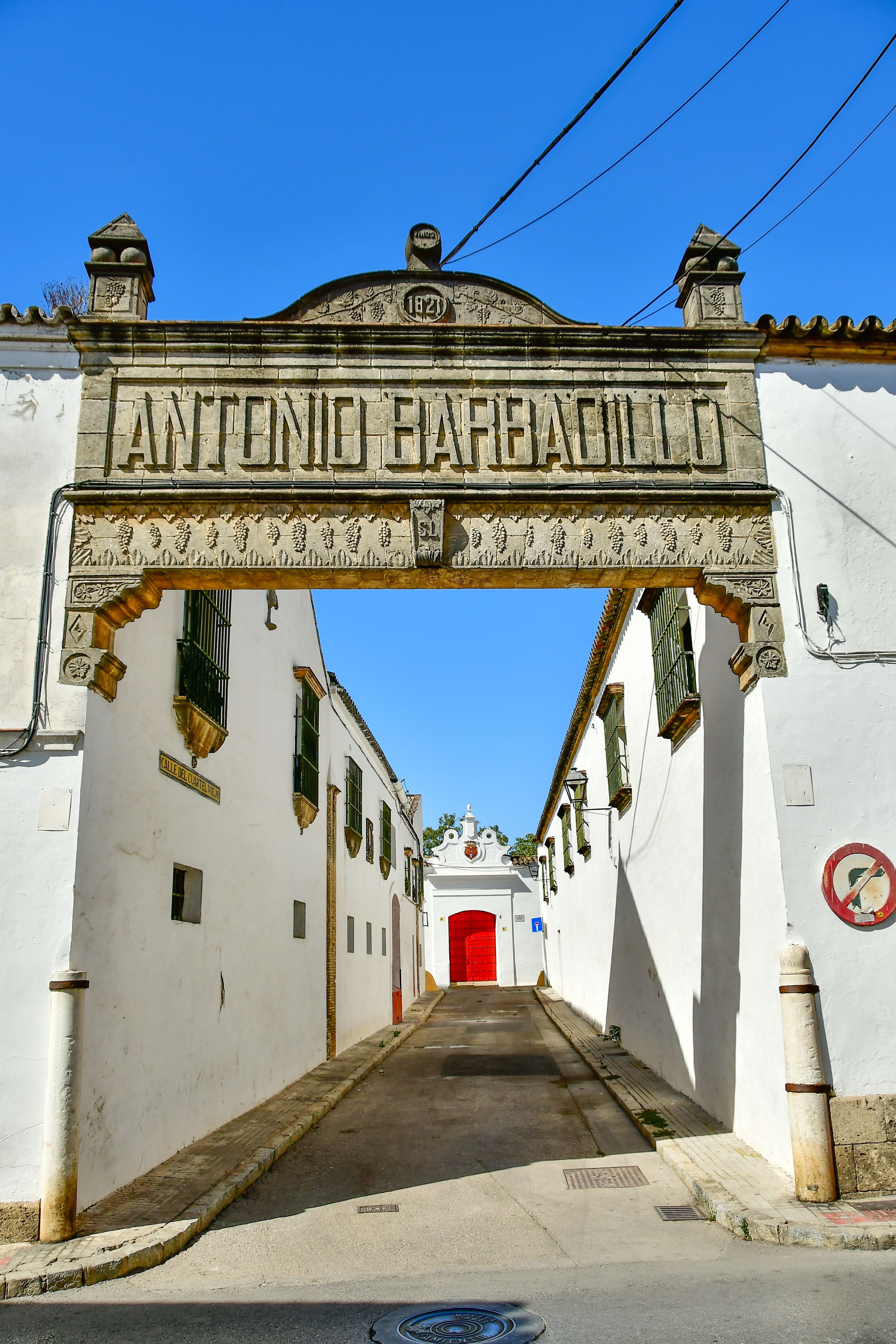 Historic Spanish street with an archway in Sanlúcar de Barrameda, Spain, under clear skies.