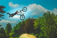 Man Holding Bike Up In The Air Under Blue Sky