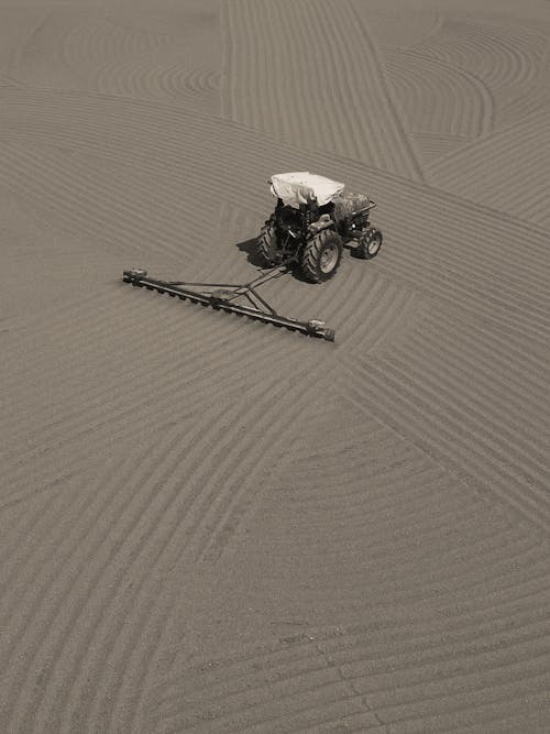 Grayscale Photography Plowing on the Sandy Ground