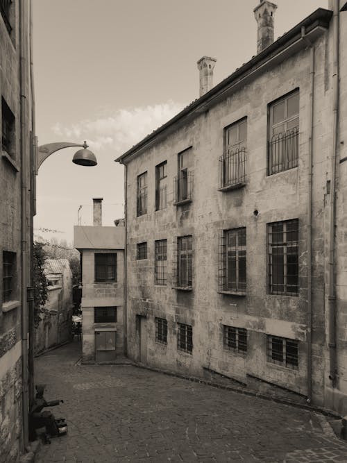 Grayscale Photography of a Narrow Street Between Concrete Houses