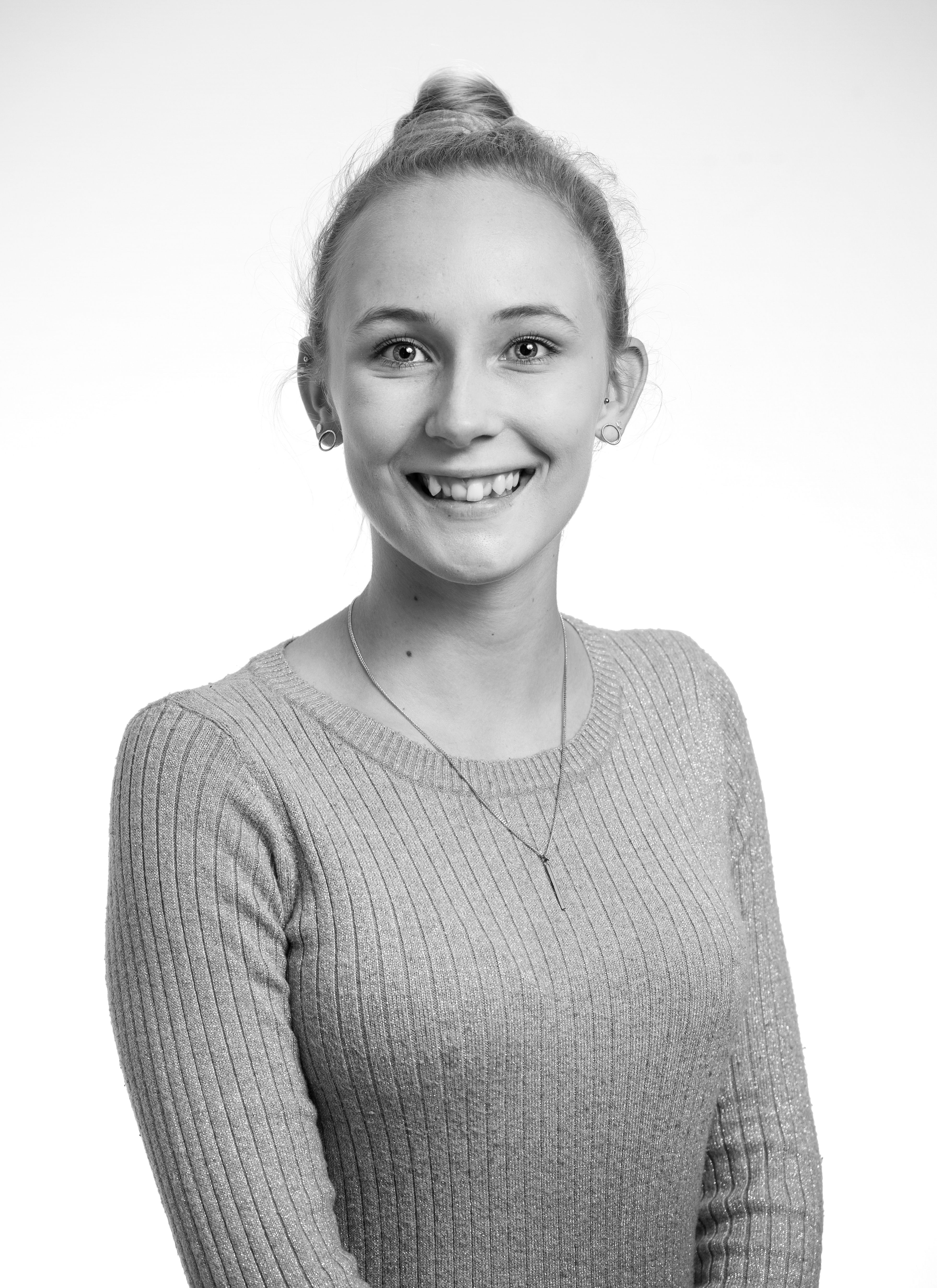 Black and white portrait of a smiling woman in a sweater against a plain background.