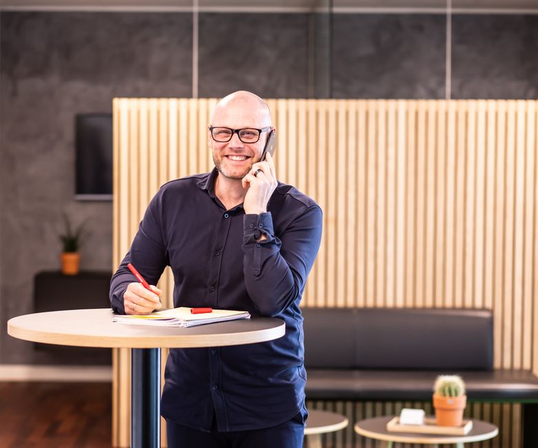 Smiling business professional on a phone call in a stylish modern office setting.