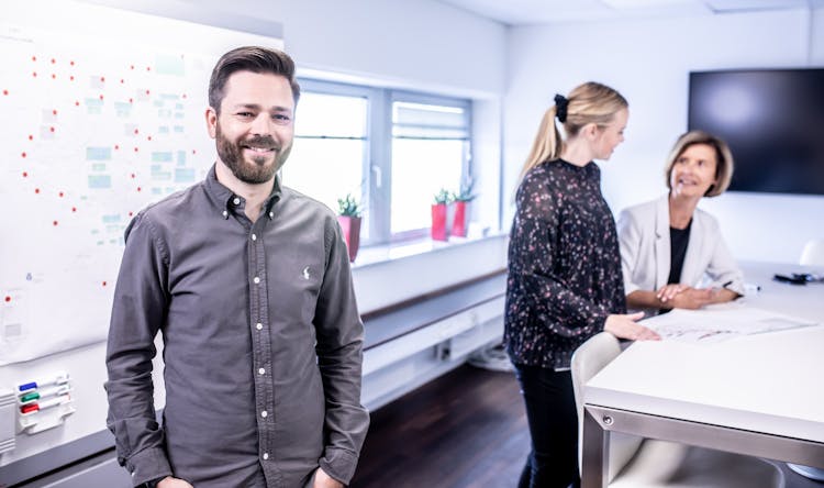 A Bearded Man In An Office With Women