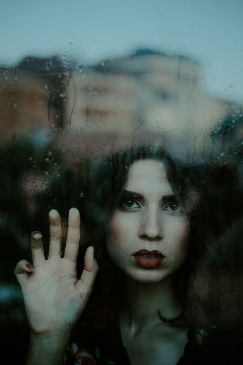 Free Woman gazing thoughtfully through a rain-streaked window in Kahramanmaraş, Turkey. Stock Photo