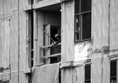 Grayscale Photo of a Man Looking Down from a Balcony