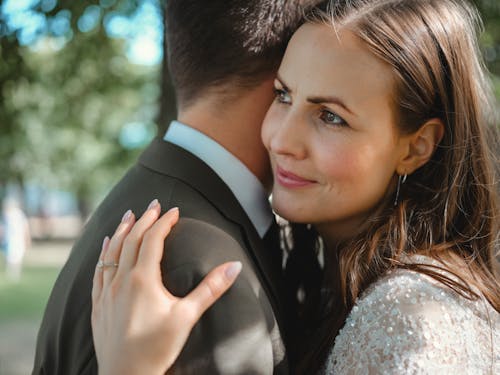 Woman in White Floral Lace Dress Hugging Man in Black Suit Jacket