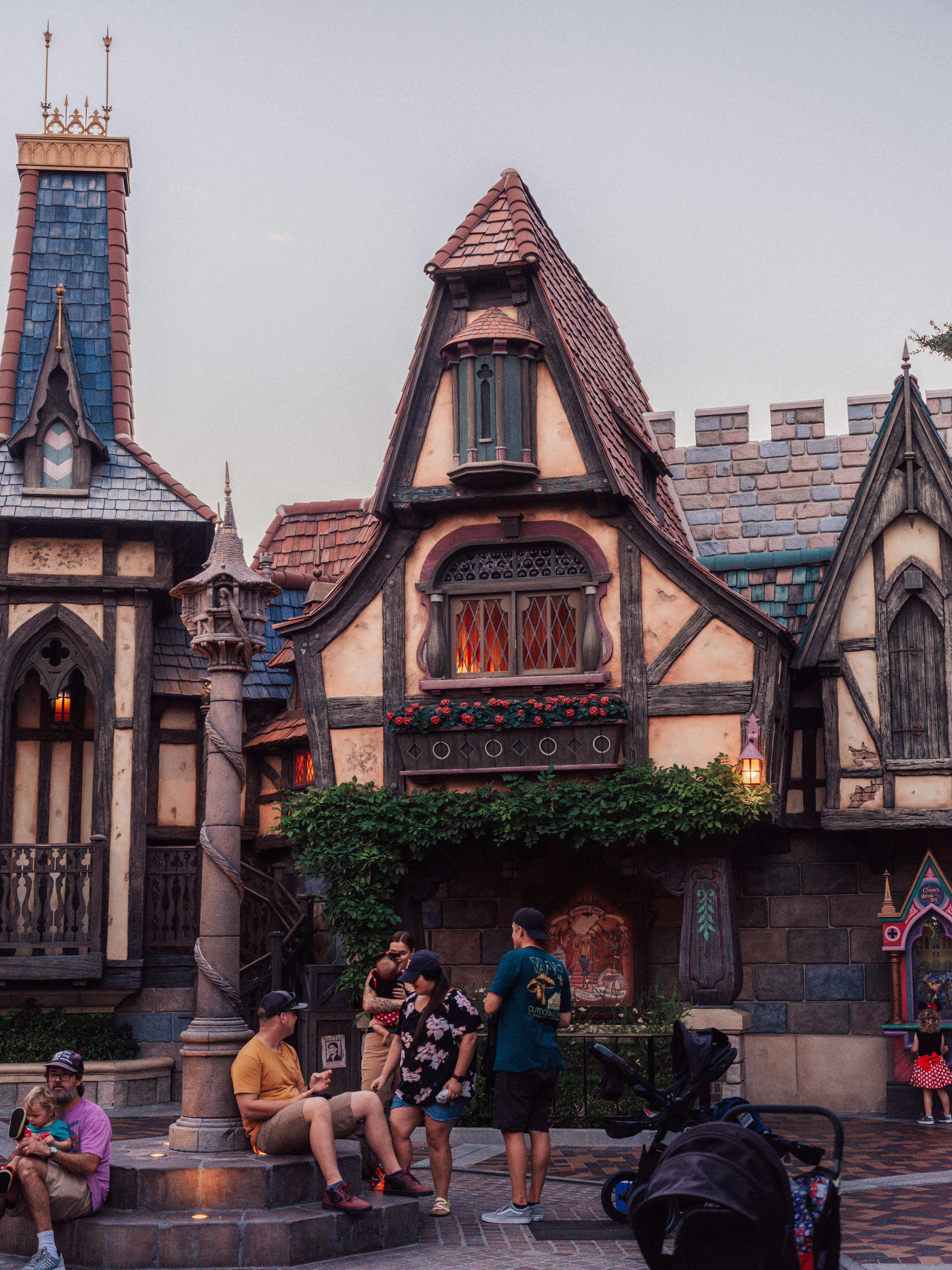 Visitors enjoying a fairytale-themed area in a popular theme park, featuring intricate architecture and a whimsical atmosphere.