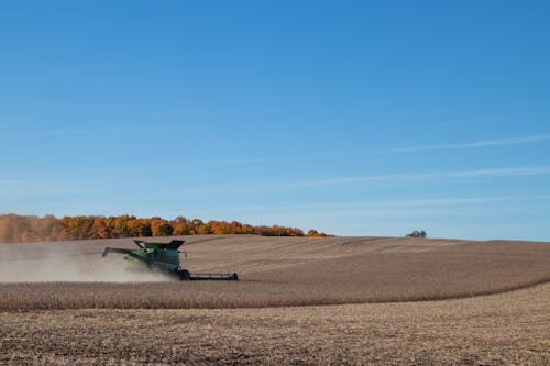 Green Combine Harvester in the Soybeans Field