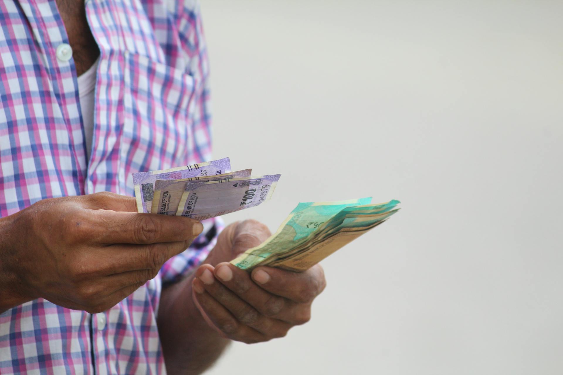 A person counts colorful banknotes, showcasing a financial transaction in detail.