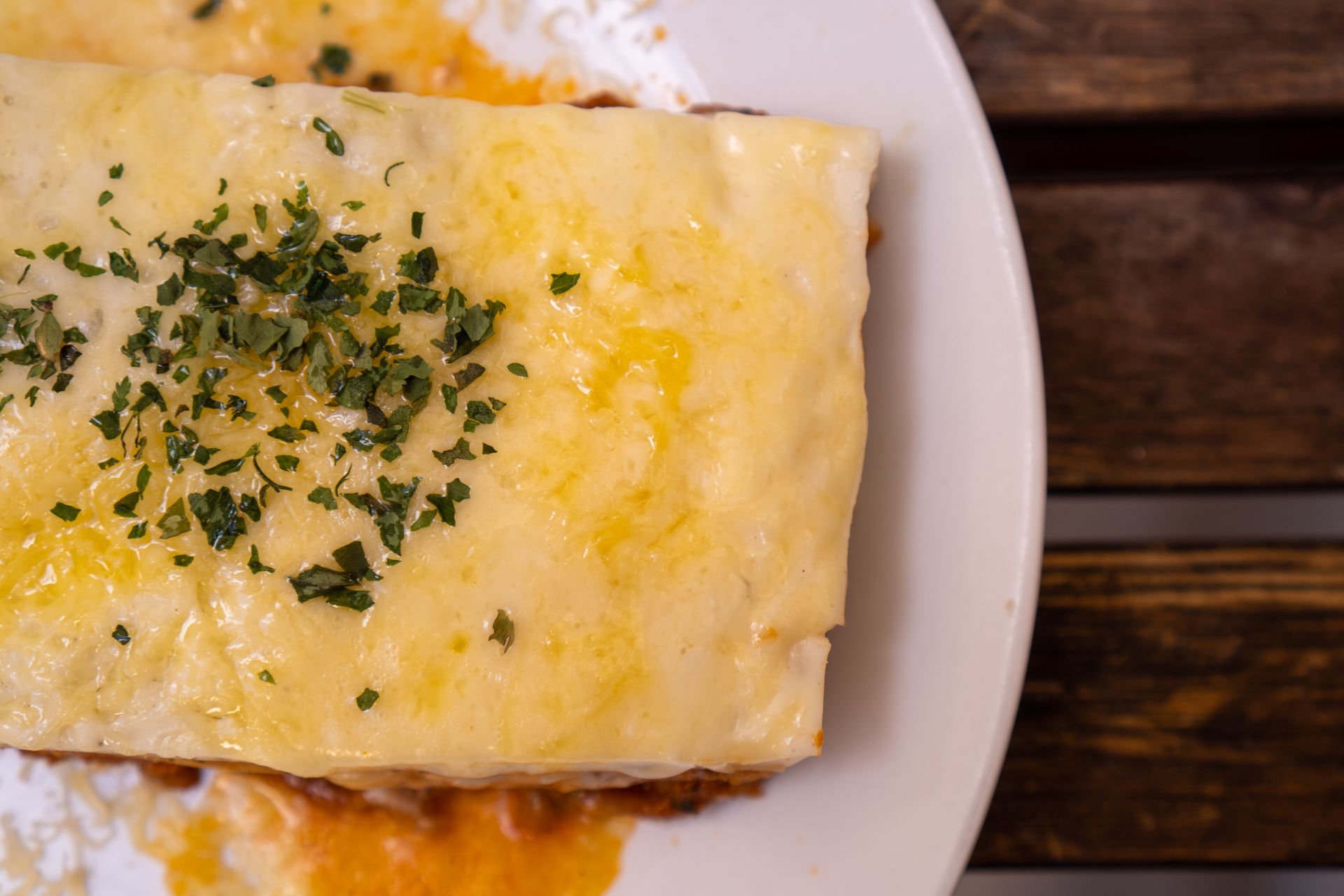 Close-up of a delicious cheesy lasagna slice topped with fresh herbs on a plate.