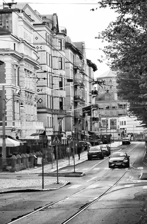 Free Grayscale image of a city street featuring historic architecture and cars, capturing urban life. Stock Photo