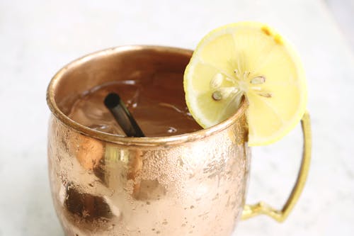 Brass Mug Filled With Clear Liquid and Slice of Lemon