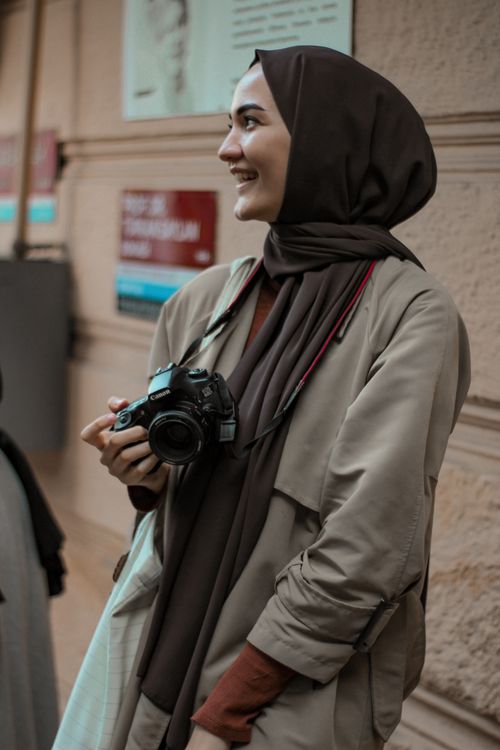Free Smiling woman in hijab holding a camera on a street in Istanbul, Türkiye. Stock Photo