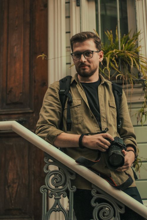 Free A bearded photographer with DSLR stands on ornate stairs in Istanbul. Stock Photo