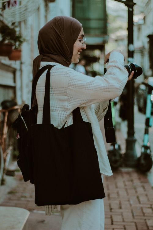 Free A smiling Muslim woman with a hijab takes photos on a street in İstanbul, Türkiye. Stock Photo
