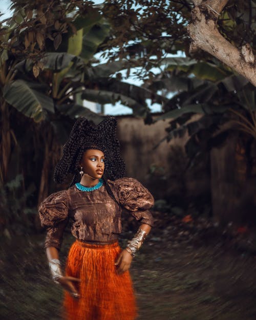 Woman with Braids Posing in Brown Blouse and Orange Skirt