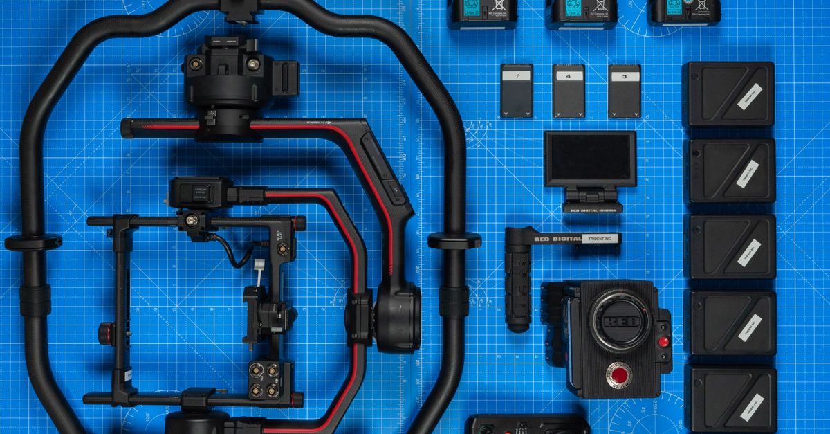 Flat lay of high-end filmmaking camera gear and accessories on a blueprint background.