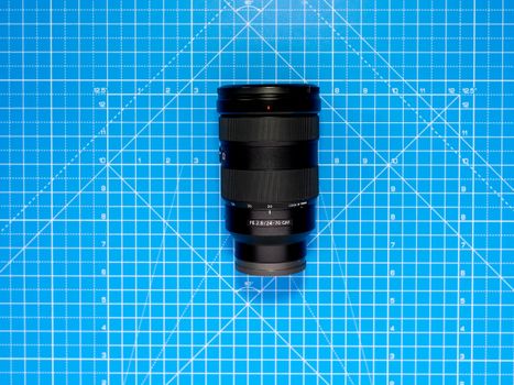 Camera lens on blue grid background, emphasizing geometrical precision.