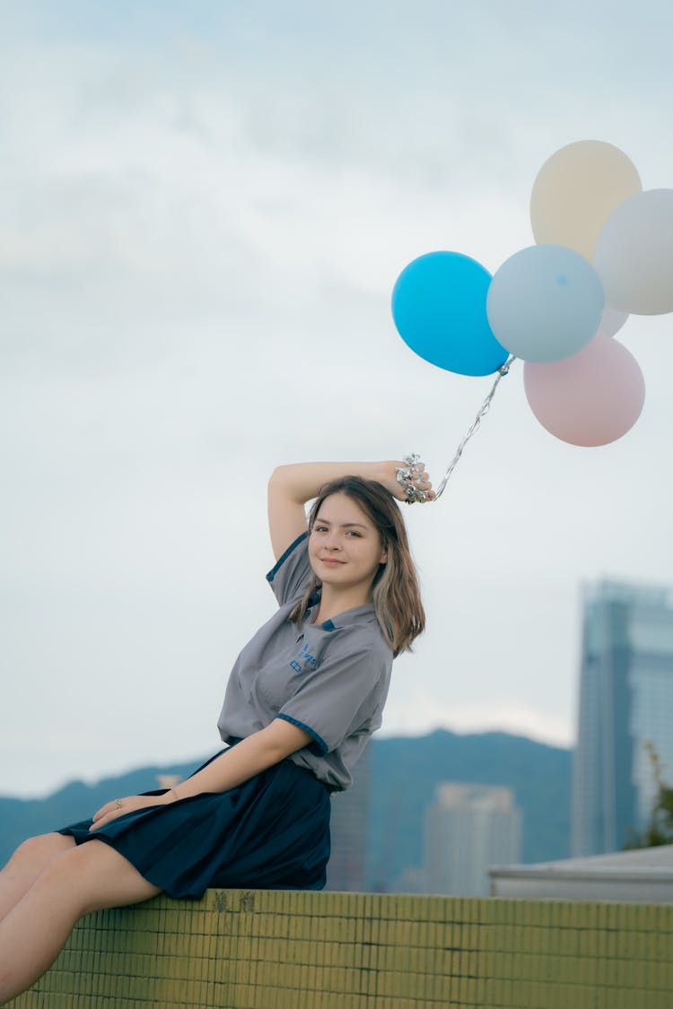 Pretty Woman Wearing A Gray Polo Holding Balloons