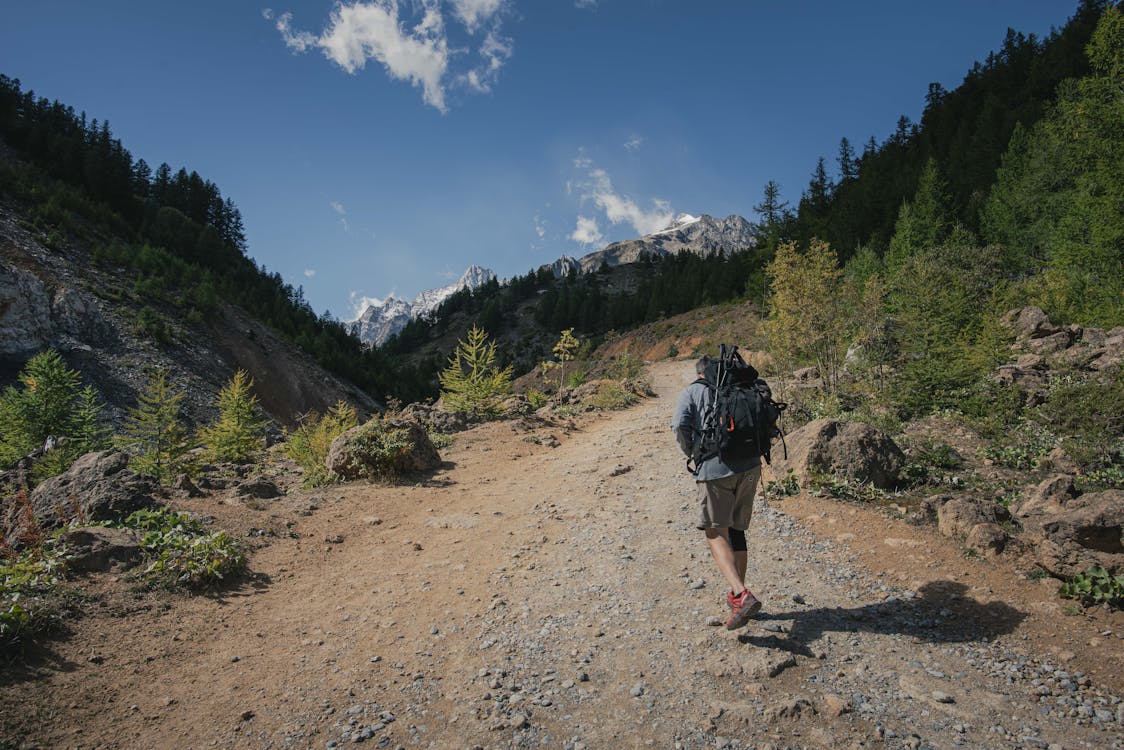 A Backpacker Walking on a Dirt Road in the Mountain