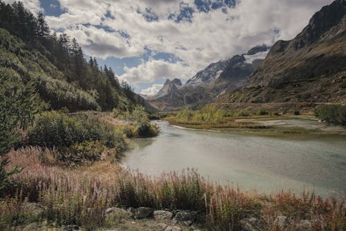 Lake Near Mountains Under White Clouds and Blue Sky