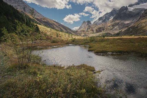 
Lake Near Mountains Under White Clouds and Blue Sky