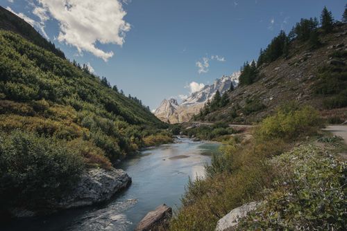 Free A serene mountain valley landscape with a winding river under a clear blue sky. Stock Photo