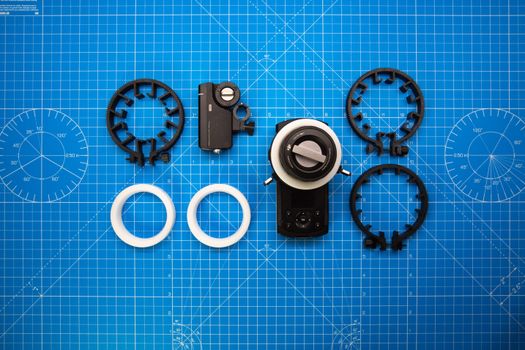 Top view of cinematography gear on a blue grid backdrop for precision setup.