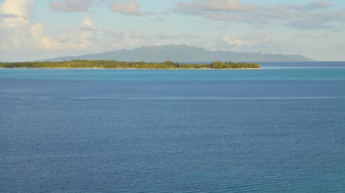 Green Island in the Middle of Blue Sea Under Blue Sky