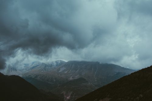Free A stunning view of mountains under a dramatic, cloudy sky with a gloomy atmosphere. Stock Photo