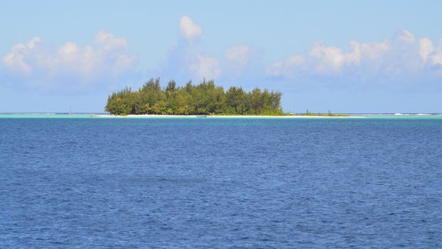A beautiful island surrounded by a clear blue sea, under a bright sky.