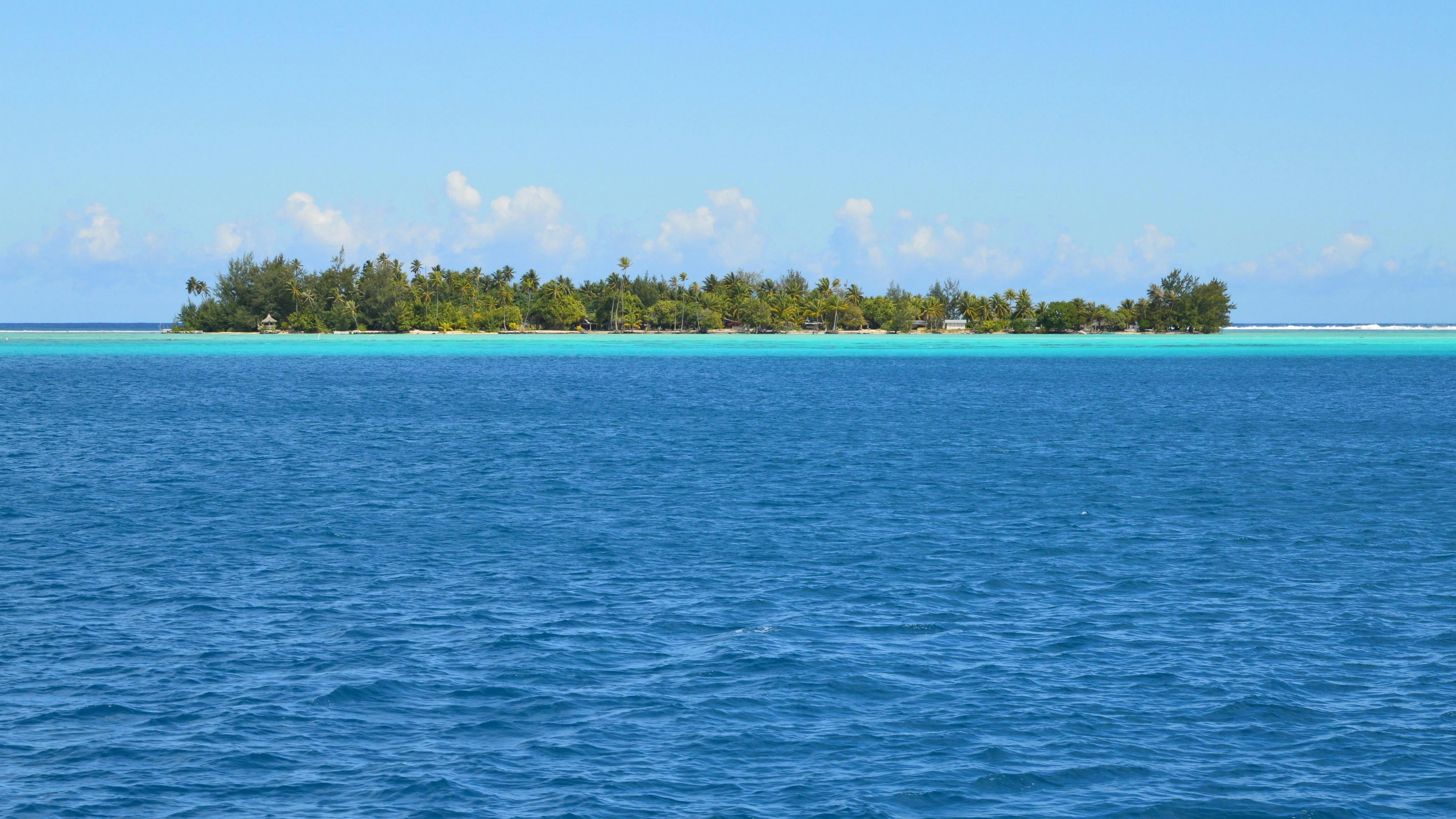 Free Idyllic island view surrounded by crystal clear blue waters under a bright sky. Stock Photo