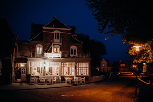 Warm evening view of Brøndums Hotel with lights and people. Perfect for travel and culture enthusiasts.