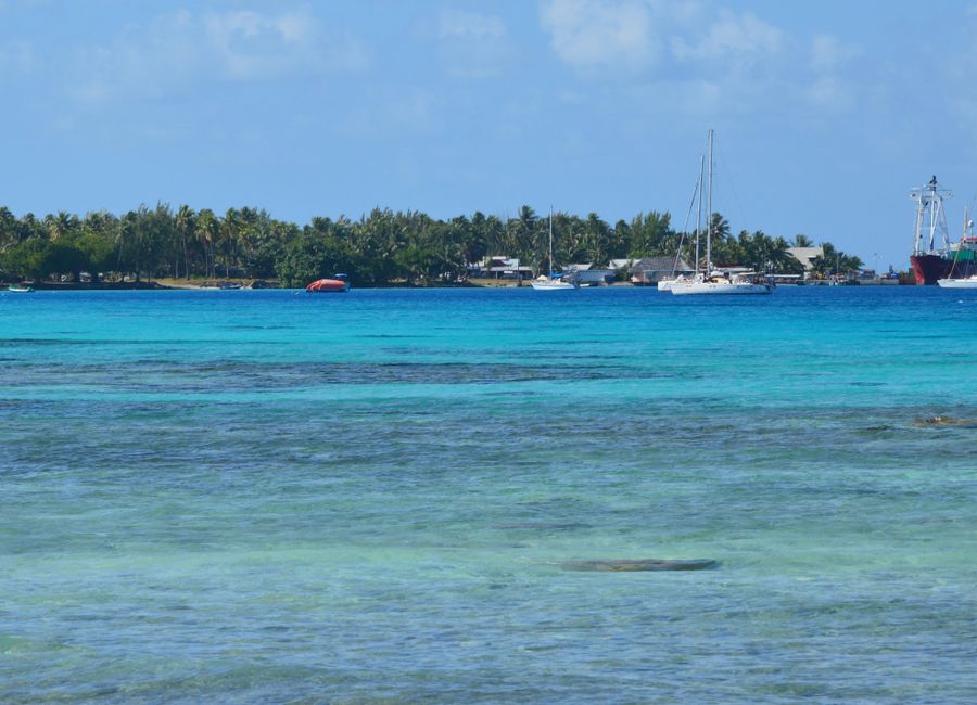 Serene tropical island scene with boats and turquoise water under a clear sky.