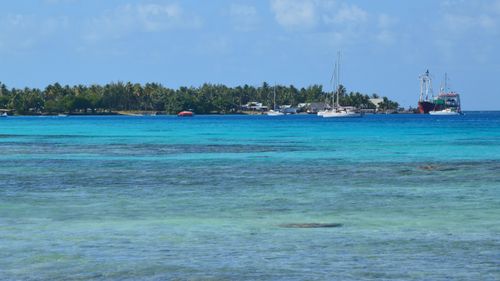 Free Serene tropical island scene with boats and turquoise water under a clear sky. Stock Photo