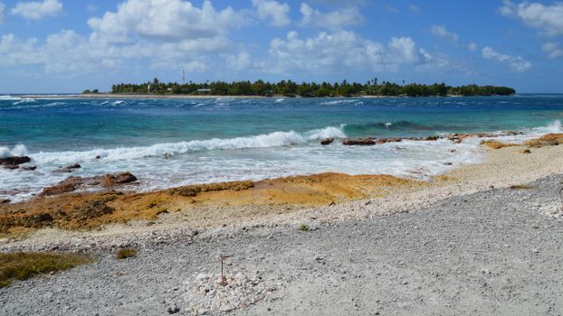 Tranquil beach scene with waves crashing on a tropical island under a blue sky.