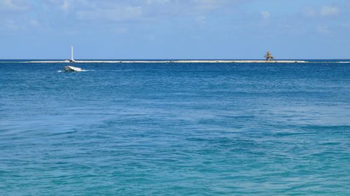 Free Serene ocean scene with a solitary boat, distant lighthouse, and small island. Stock Photo