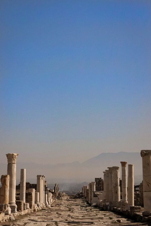Free Stone pillars of ancient ruins extend under a clear blue sky, embodying historic architecture. Stock Photo