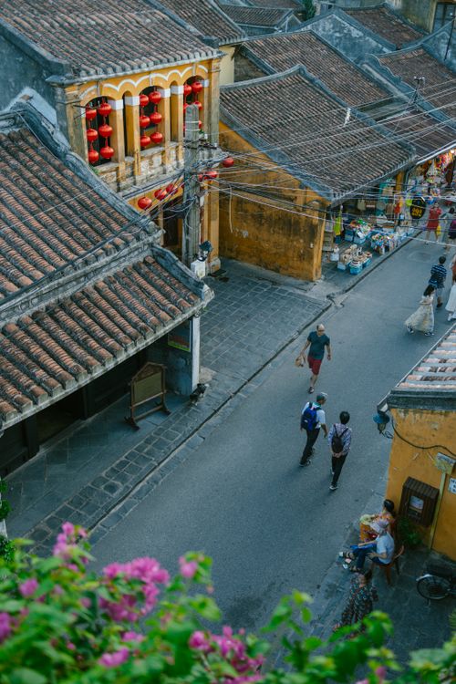 Free High-angle shot capturing people walking along a bustling street in a historic district with vibrant buildings. Stock Photo