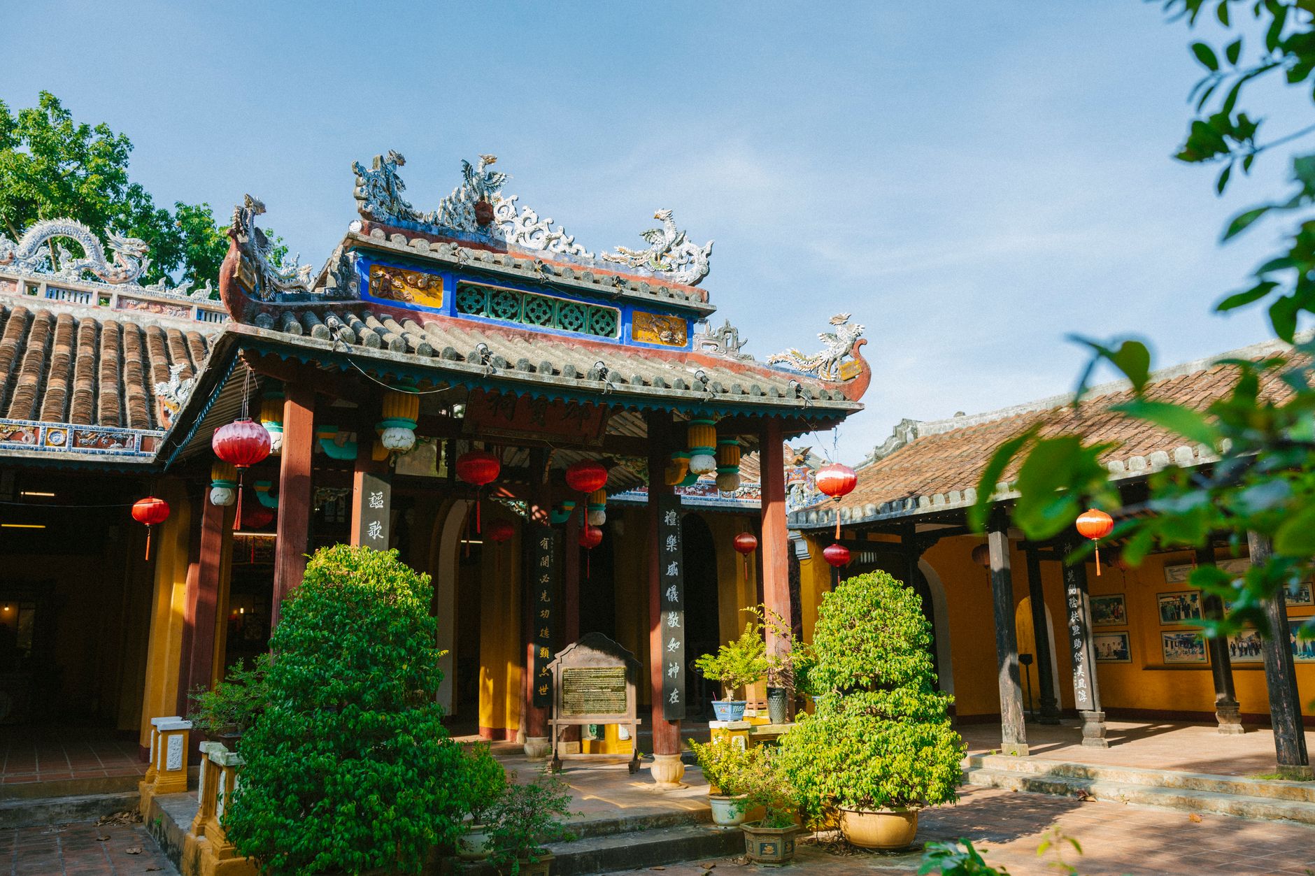 Scenic view of a Vietnamese temple facade adorned with red lanterns and lush greenery.