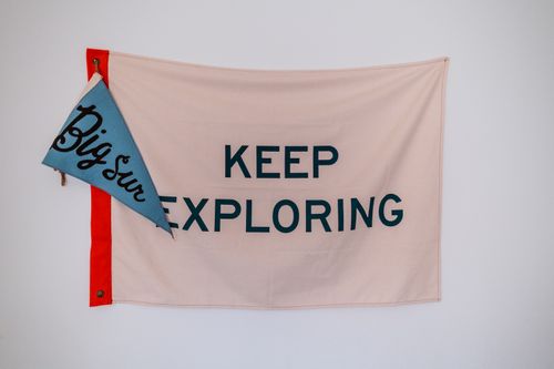 Free A motivational 'Keep Exploring' flag with 'Big Sur' pennant on a white background. Stock Photo