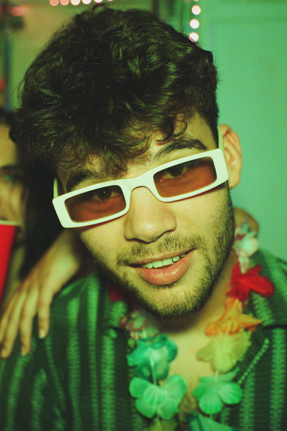 Joven en una fiesta con gafas de sol y collar de flores de estilo hawaiano
