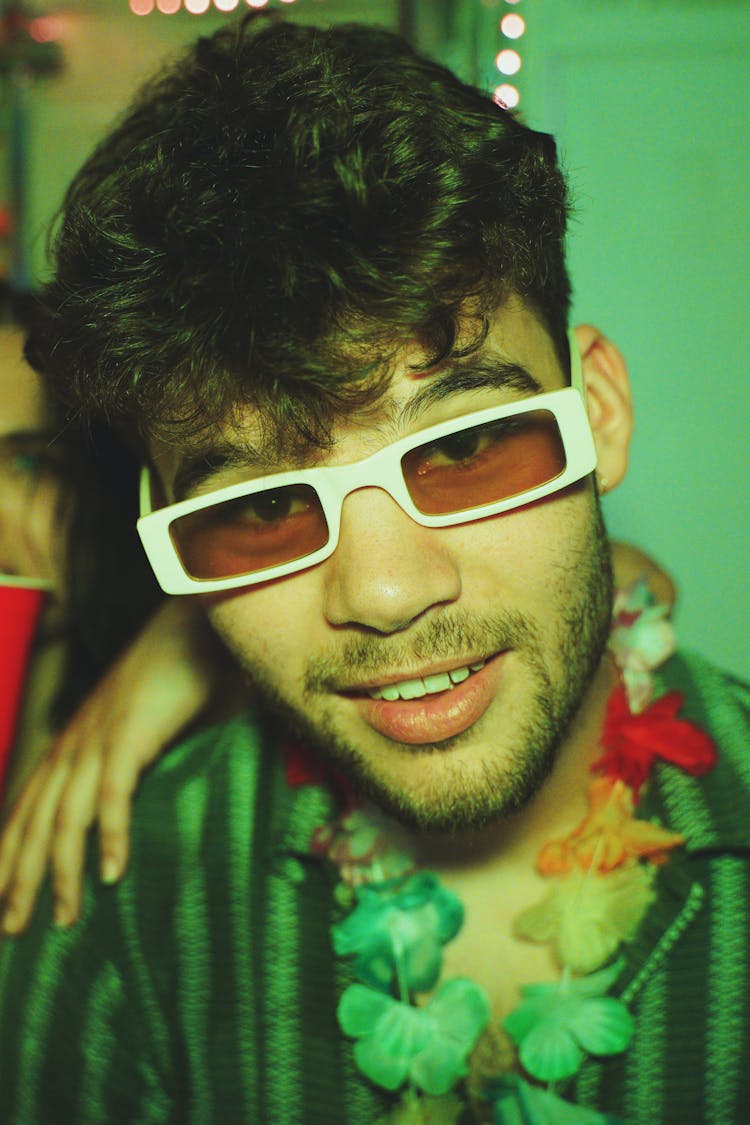 Young Man On A Party Wearing Sunglasses And Hawaiian Flower Necklace 